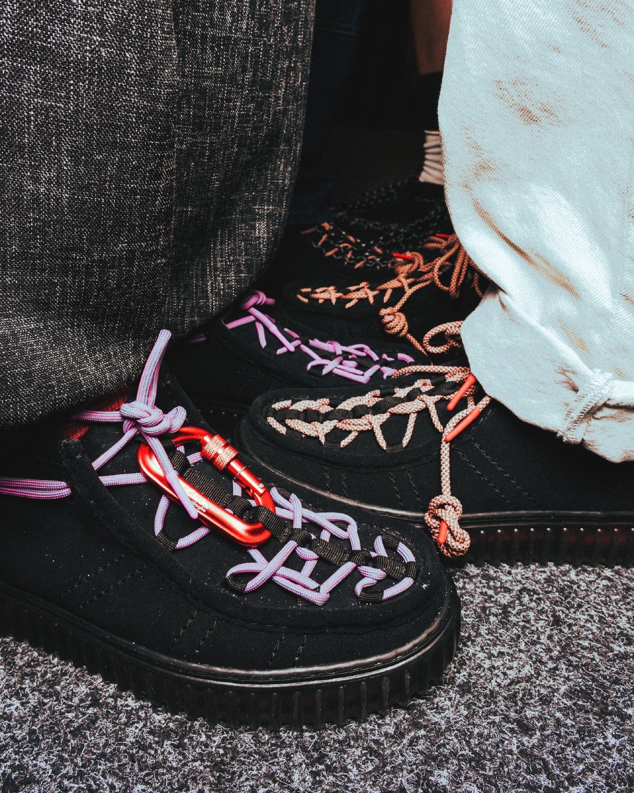 Detalle de las Clarks Originals x Topologie Torhill Hi Black Interest en ante negro, con cordones técnicos violetas y mosquetón rojo de climbing