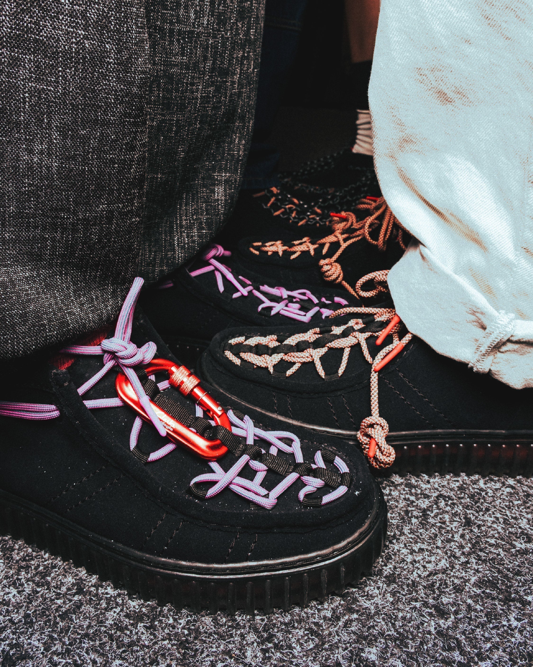 Detalle de las Clarks Originals x Topologie Torhill Hi Black Interest en ante negro, con cordones técnicos violetas y mosquetón rojo de climbing