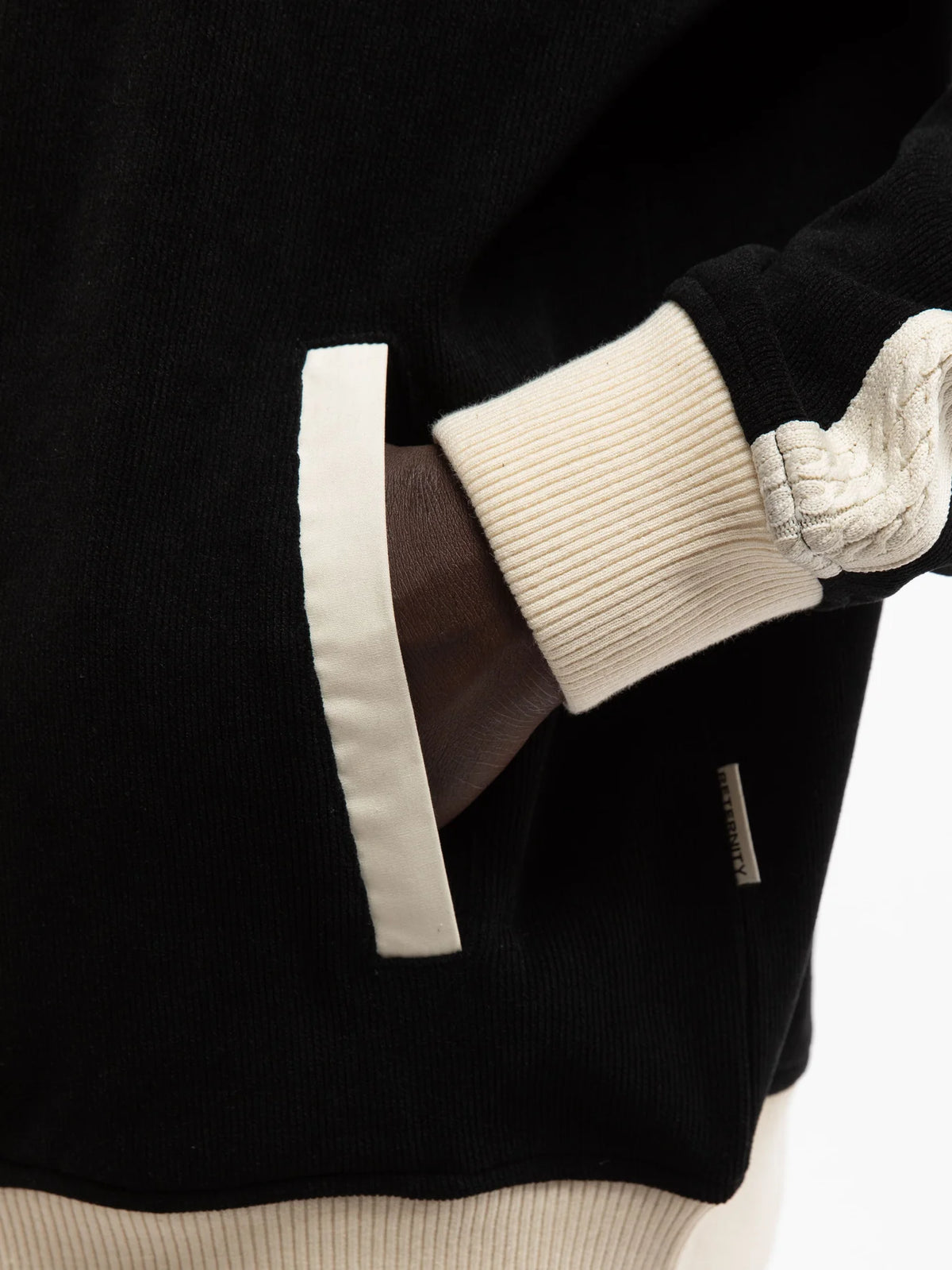 Detalle del puño acanalado en contraste crema de la chaqueta Reternity Studio Knit Track negra