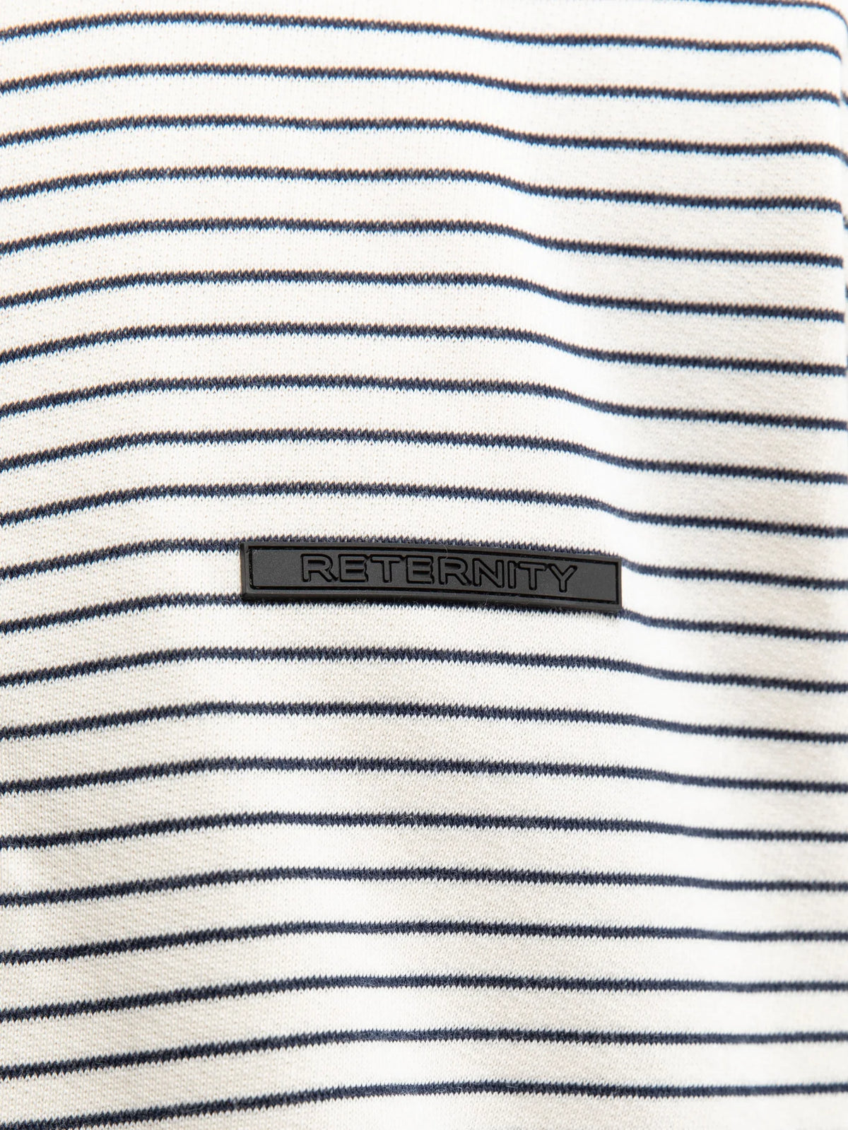 Detalle del tejido a rayas crudo y azul marino con etiqueta Reternity de la camiseta Henley Stripe
