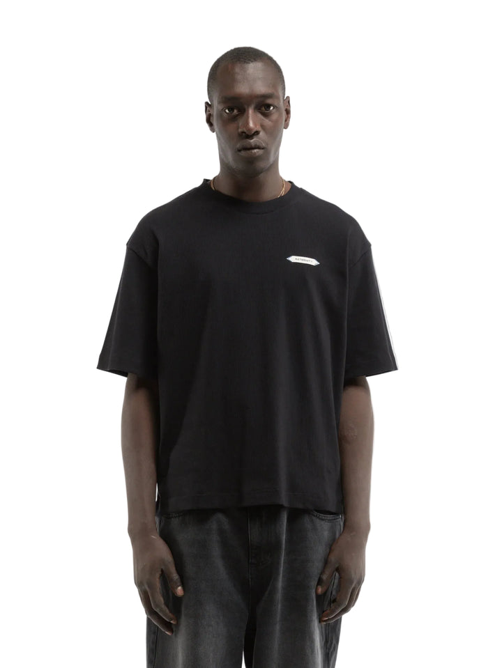 Hombre con la camiseta Reternity L'Atelier Line Rib negra y pantalón claro, look completo de cuerpo entero