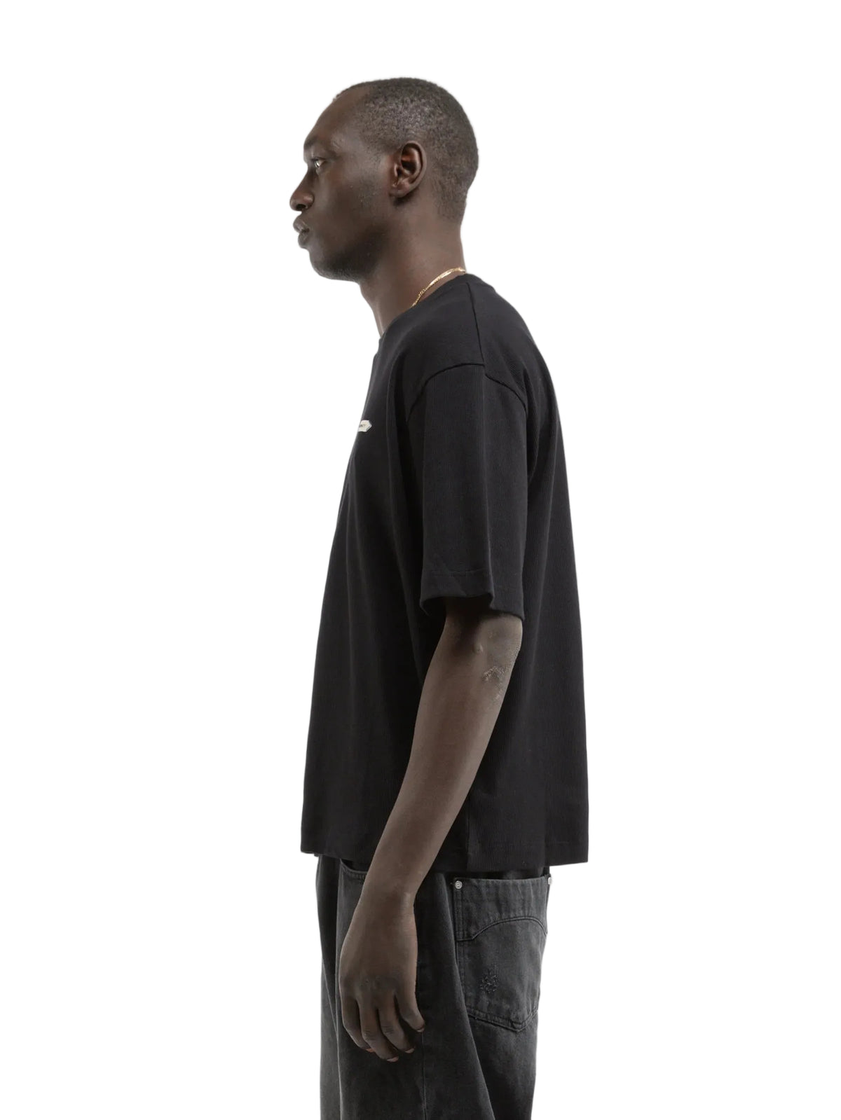 Hombre de perfil con la camiseta Reternity L'Atelier Line Rib negra, cuerpo entero