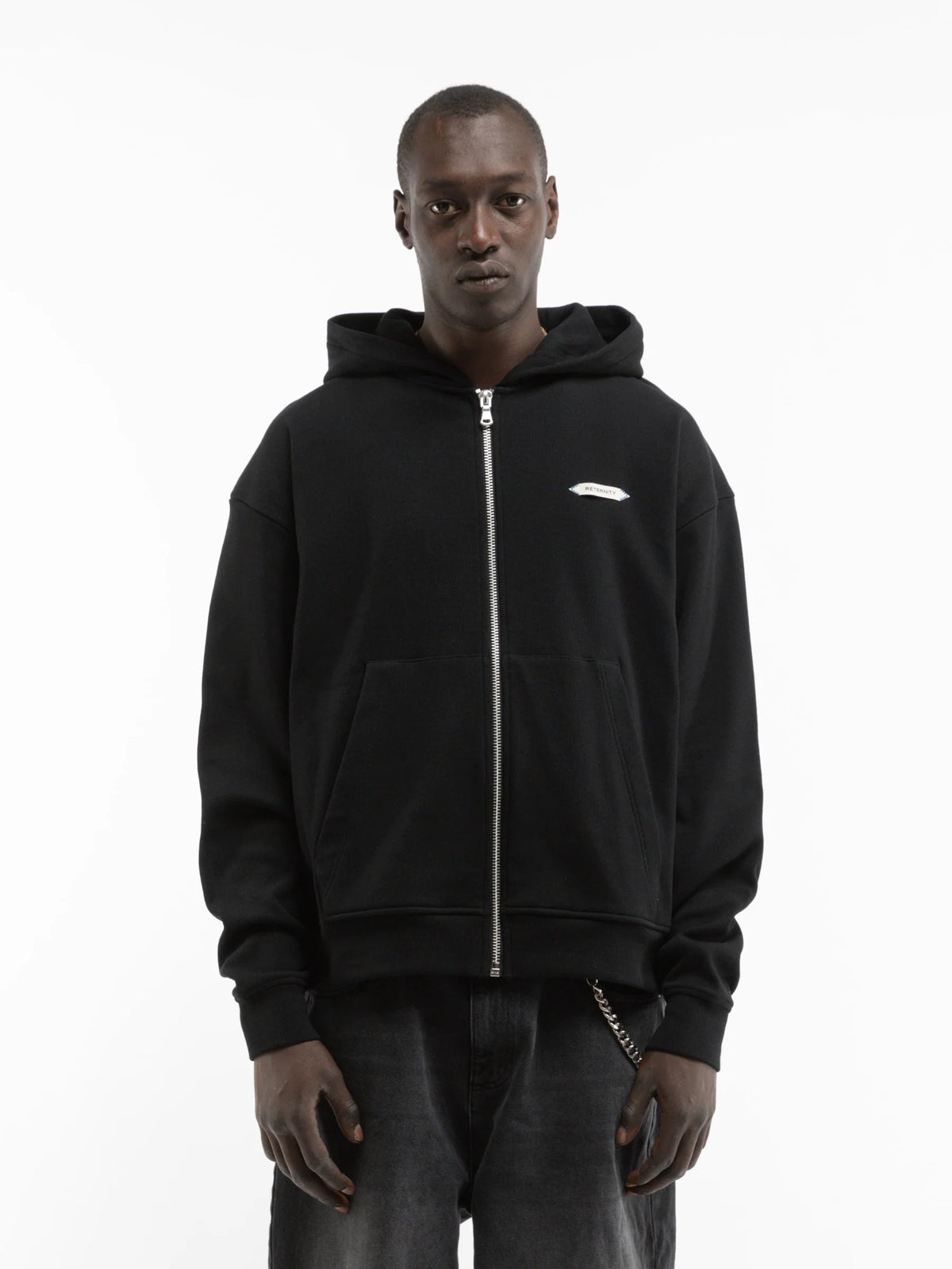 Hombre con la sudadera con capucha y cremallera Reternity L'Atelier Line Zip negra y vaqueros oscuros, look completo