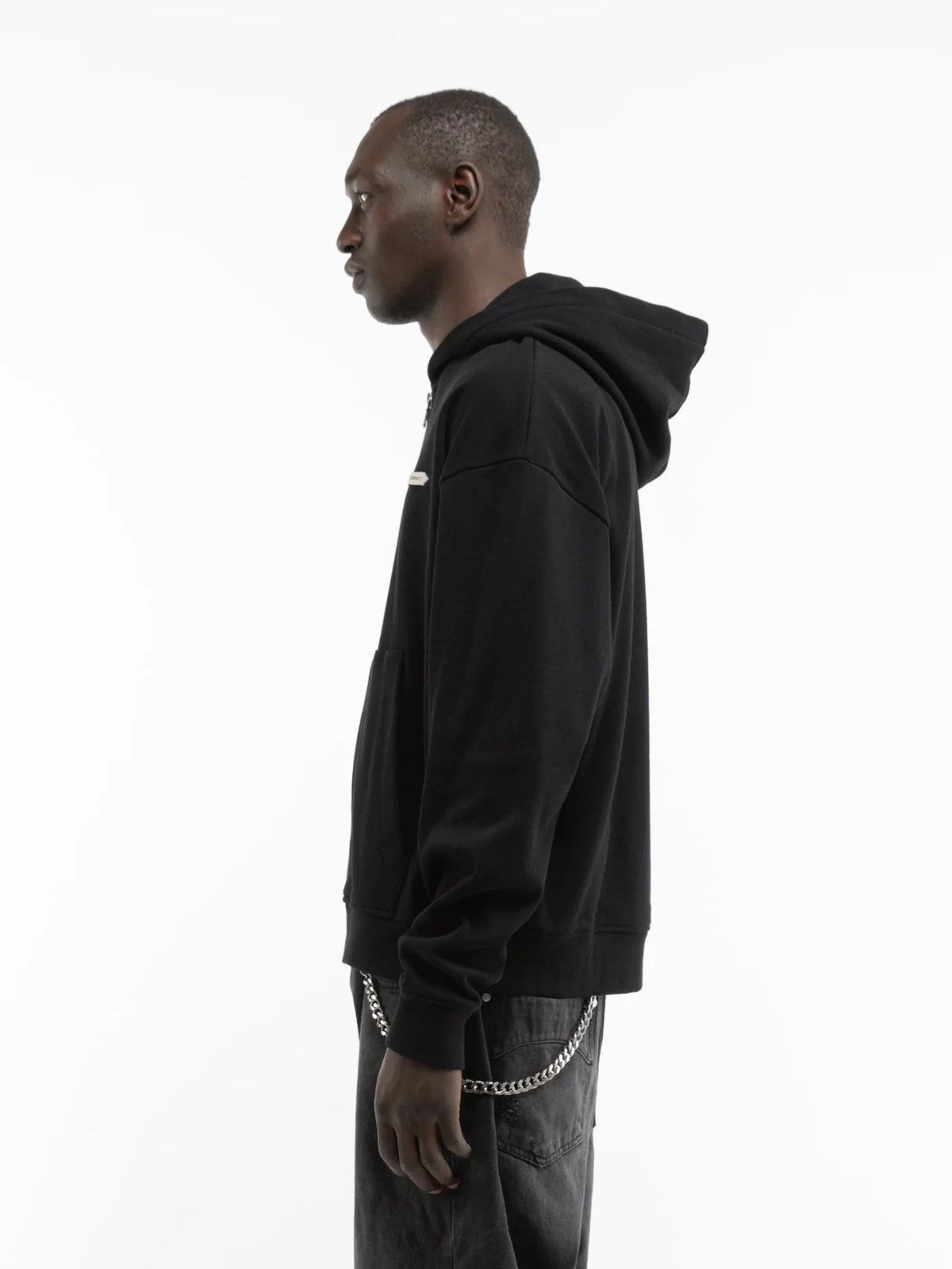 Hombre de perfil con la sudadera con capucha y cremallera Reternity L'Atelier Line Zip negra, cuerpo entero