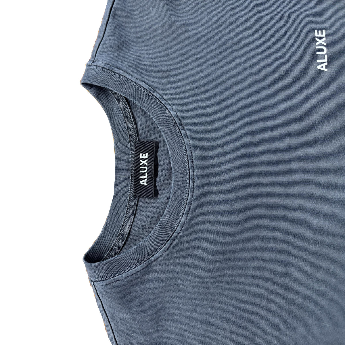 Detalle del cuello con etiqueta ALUXE de la camiseta Release gris washed