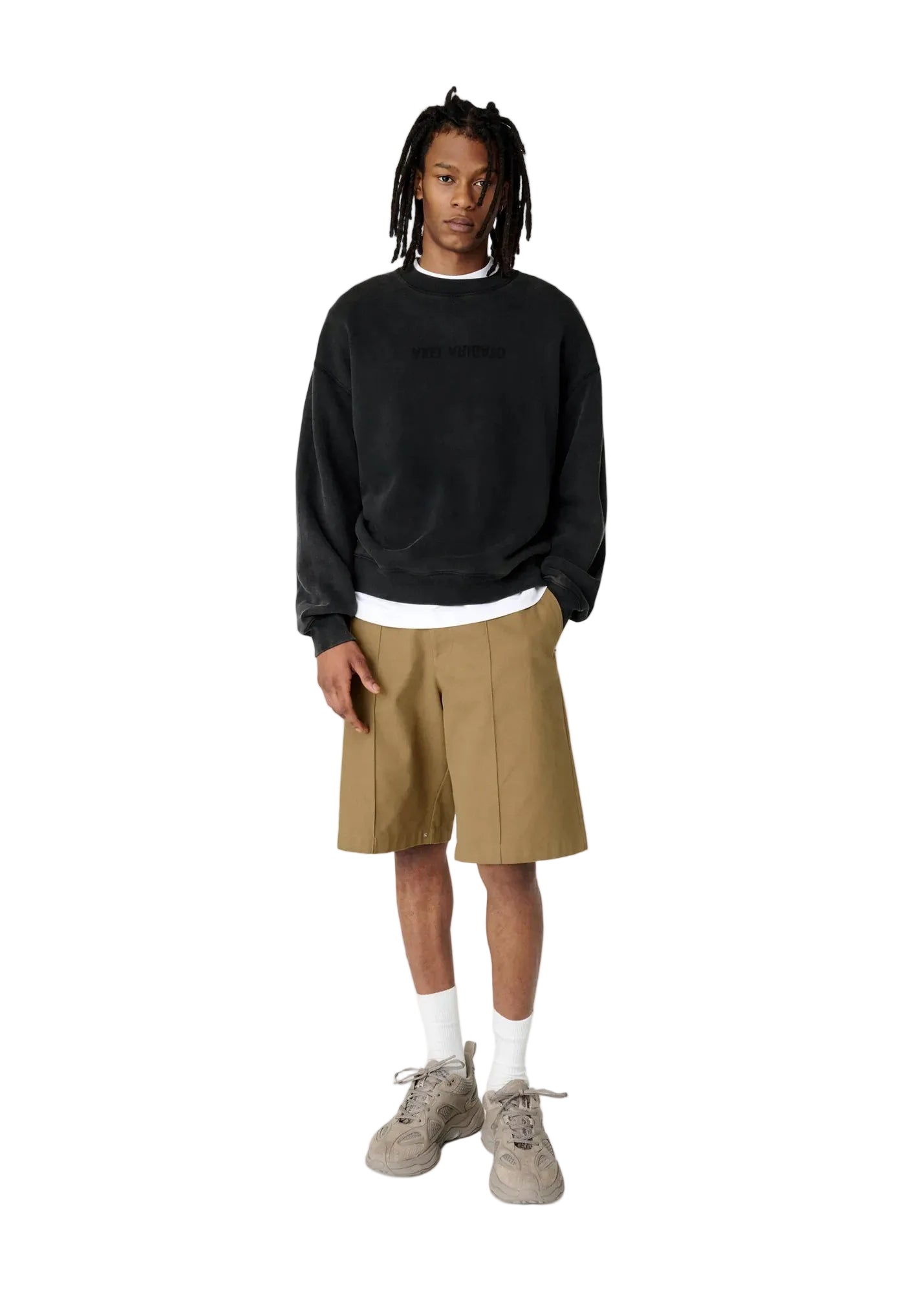 Hombre con la sudadera Axel Arigato Distort Washed negra oversized, pantalón corto beige y zapatillas blancas, look completo