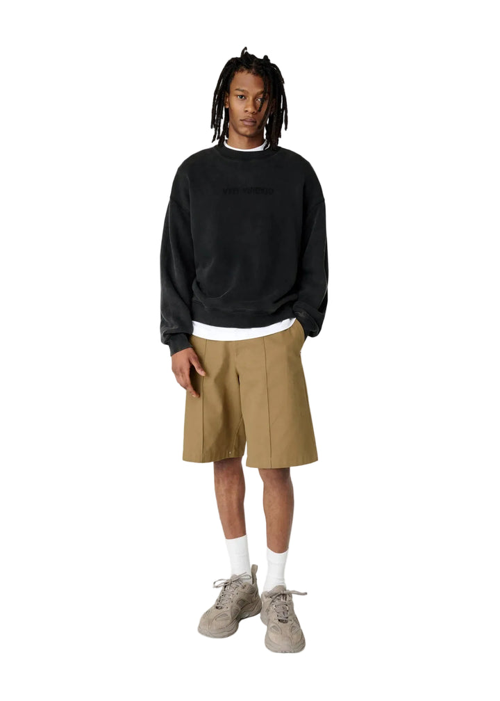 Hombre con la sudadera Axel Arigato Distort Washed negra oversized, pantalón corto beige y zapatillas blancas, look completo
