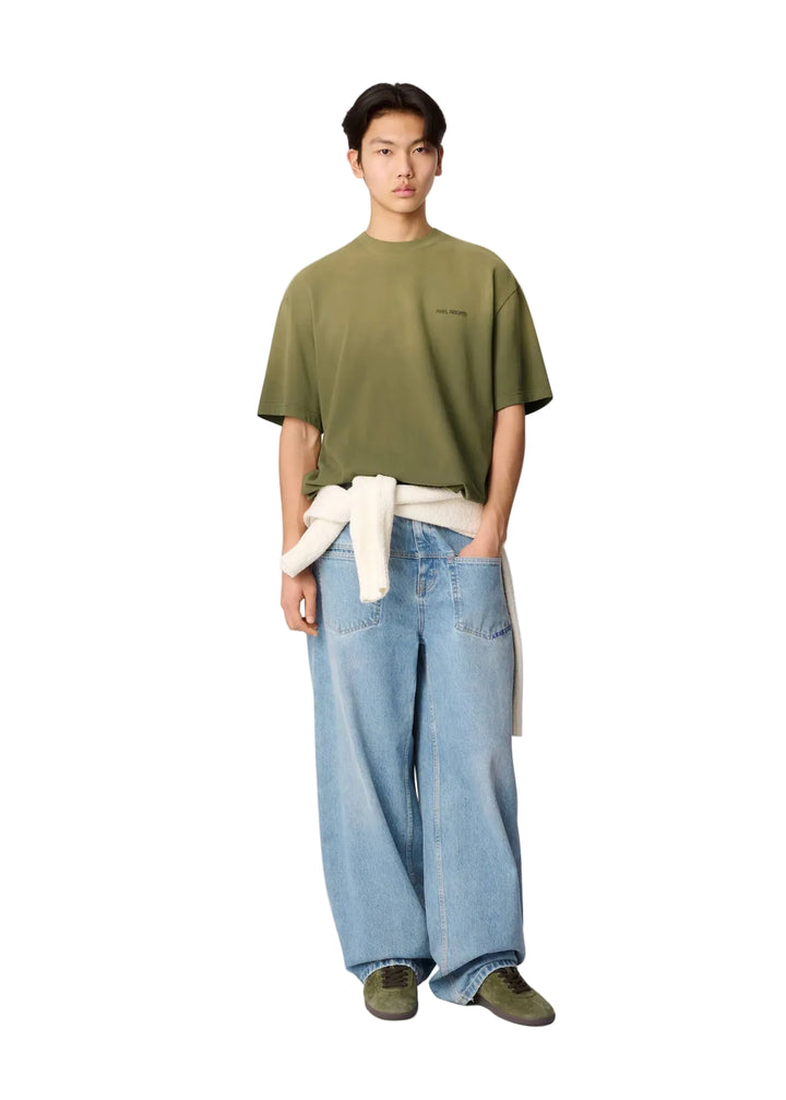 Hombre con la camiseta Axel Arigato Gradient verde oliva oversized, vaqueros claros y look completo