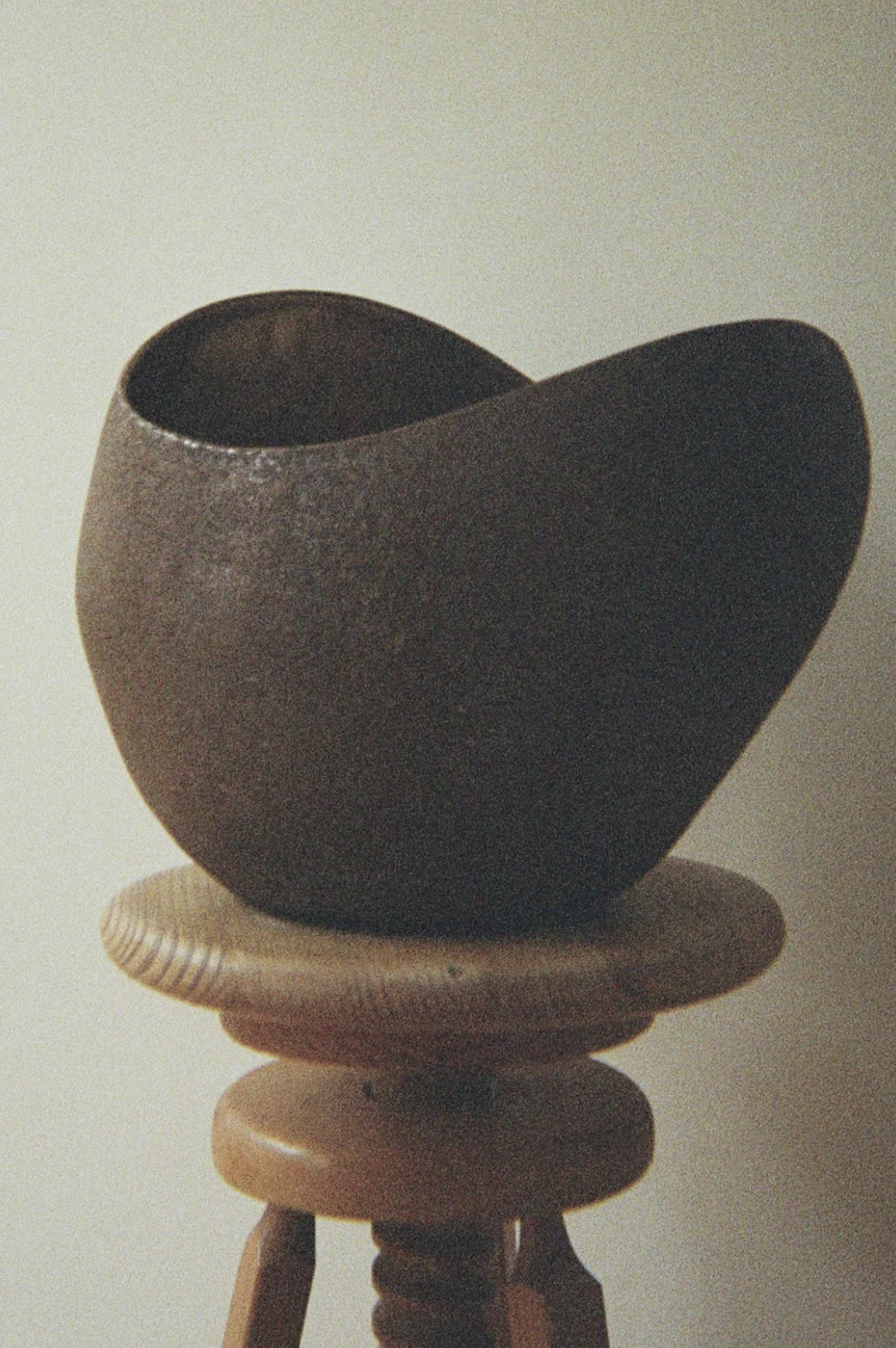 Vela escultura AMBER LIGHT de AMEN en marrón mate, colocada sobre un taburete de madera