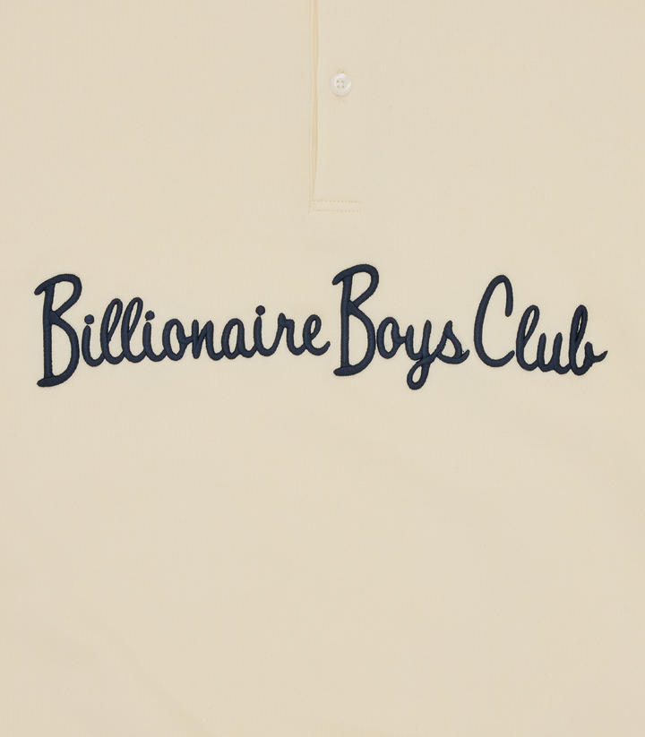 Detalle del script Billionaire Boys Club en azul marino sobre el pecho de la sudadera crema