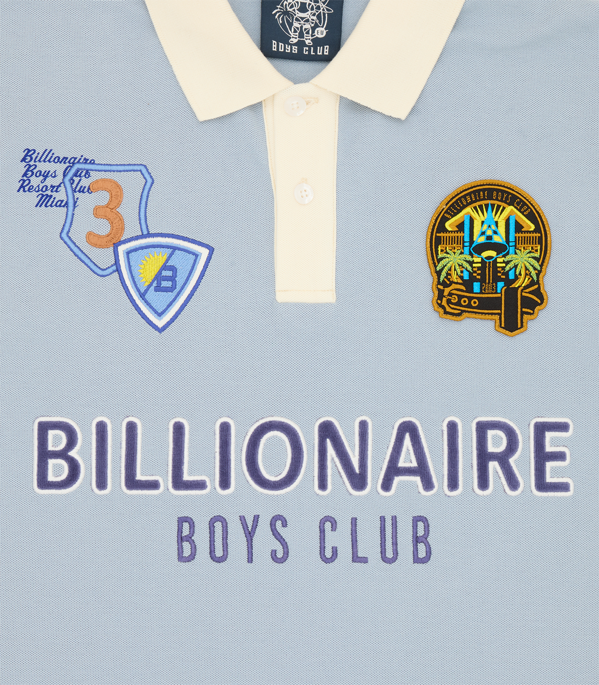 Detalle del cuello crema y los parches bordados en el hombro del polo Billionaire Boys Club Resort azul claro
