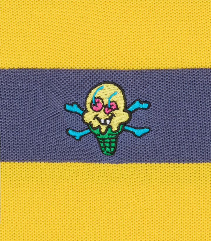 Detalle del logo Cones & Bones bordado sobre las rayas azul y amarillo del polo ICECREAM