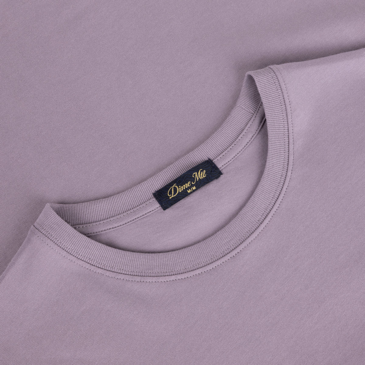 Detalle de la etiqueta interior Dime MTL en el cuello de la camiseta plum gray