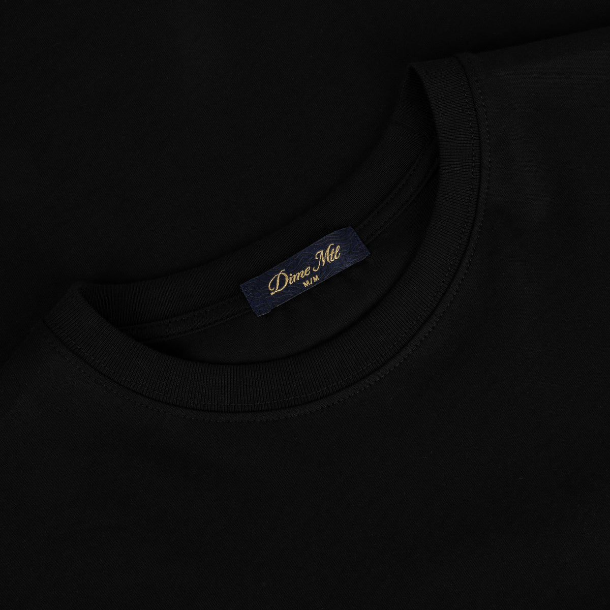 Detalle de la etiqueta interior Dime MTL en el cuello de la camiseta negra