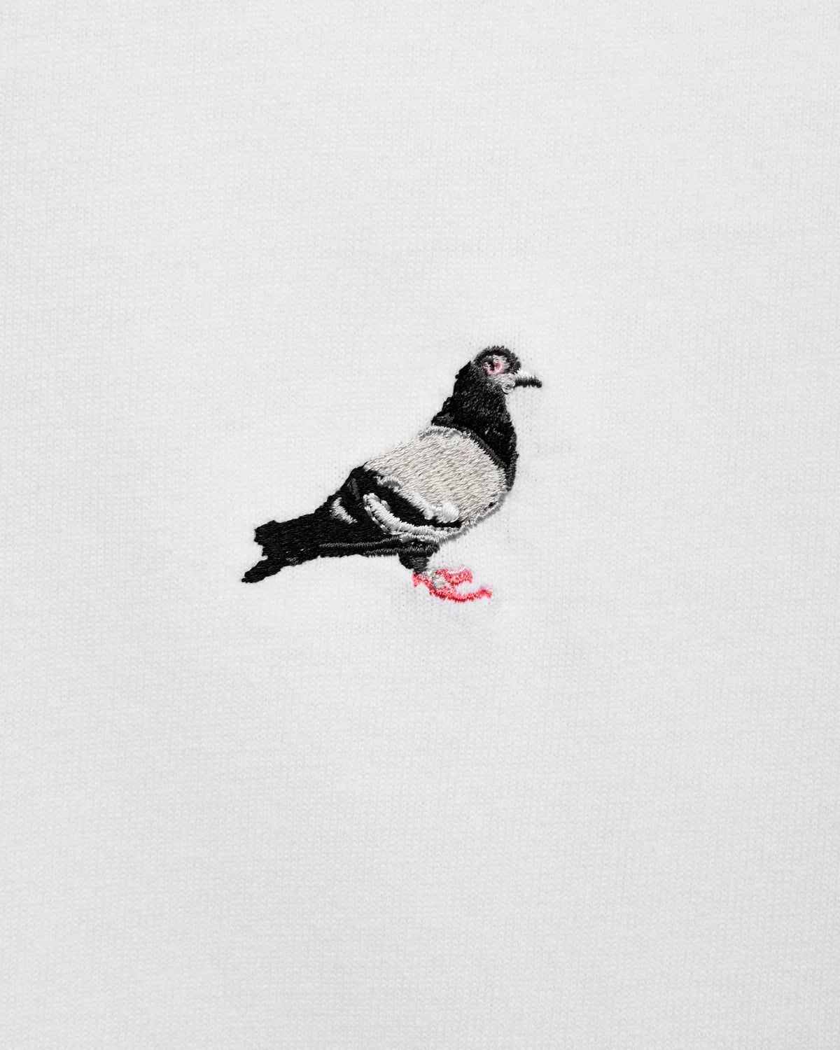 Detalle del logo Pigeon bordado en alta densidad sobre la camiseta Staple blanca