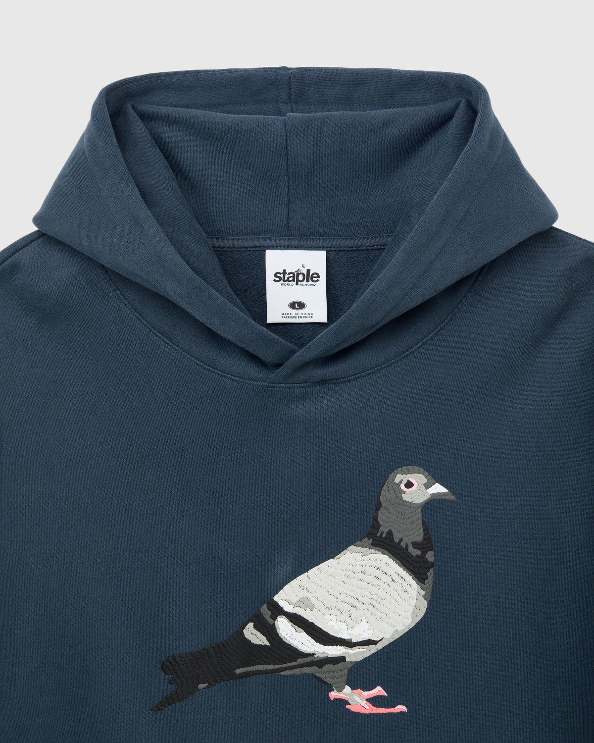 Detalle de la capucha y el print de la paloma en el pecho de la sudadera Staple azul marino
