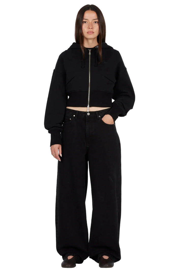 Modelo con sudadera Dime Cropped Zip Hoodie negra y pantalón ancho negro, vista frontal