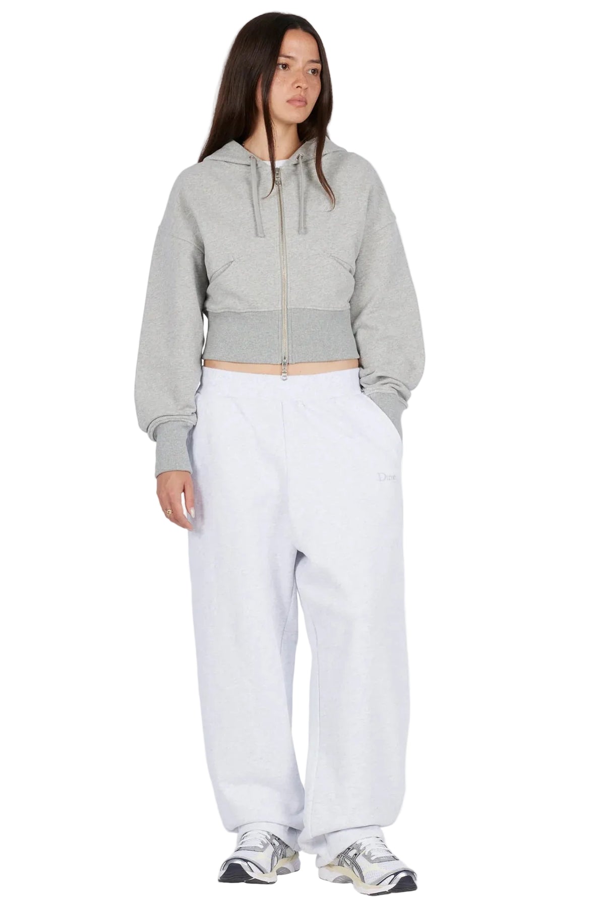 Modelo con sudadera Dime Cropped Zip Hoodie gris jaspeado y pantalón blanco, vista frontal