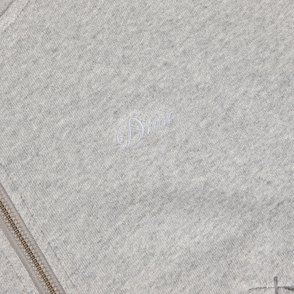 Detalle del logo Dime bordado y la cremallera metálica de la sudadera gris jaspeado