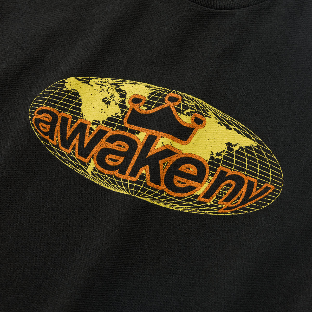 Detalle del estampado del globo terráqueo con awake ny en amarillo sobre la camiseta negra