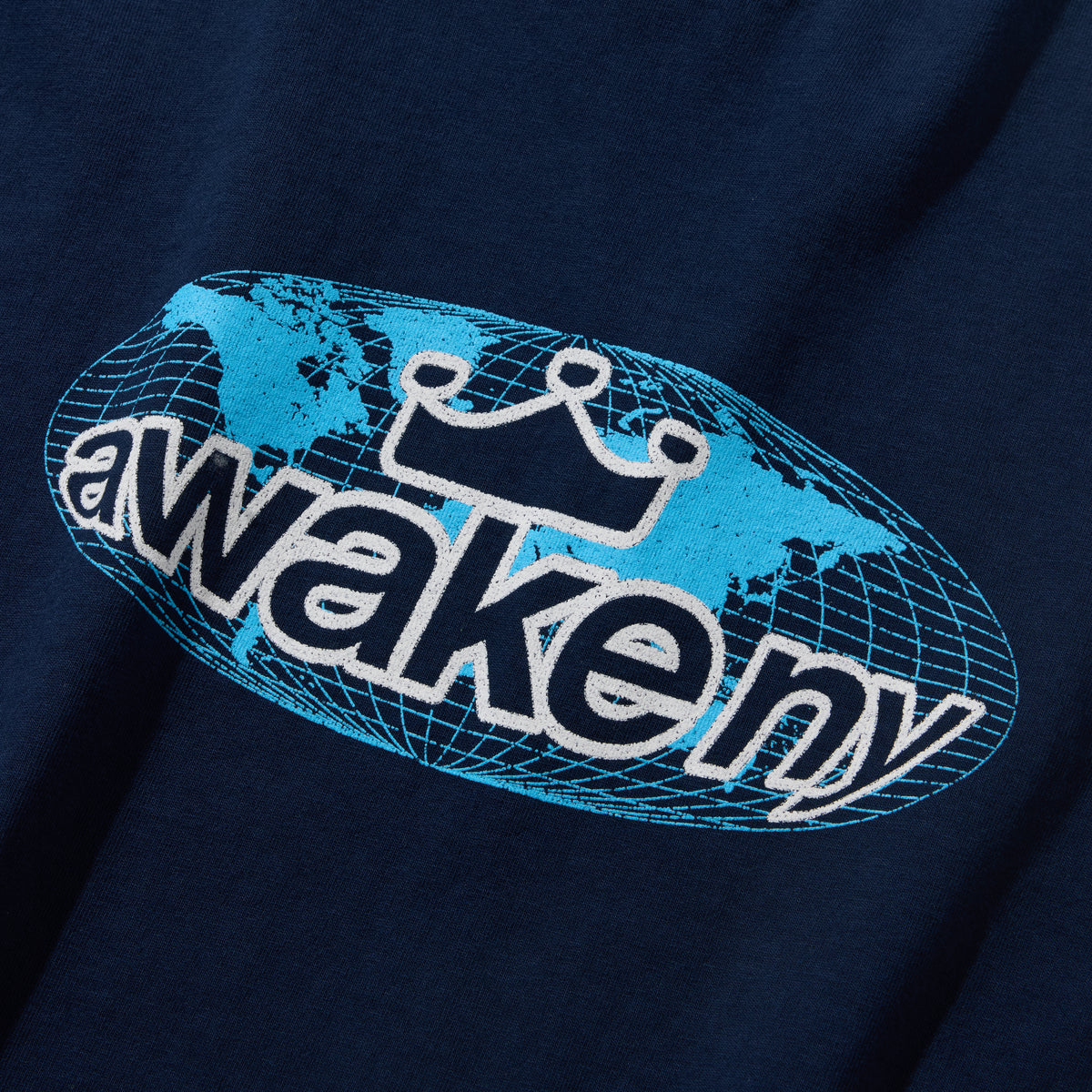 Detalle del estampado del globo terráqueo con awake ny en celeste sobre la camiseta azul marino