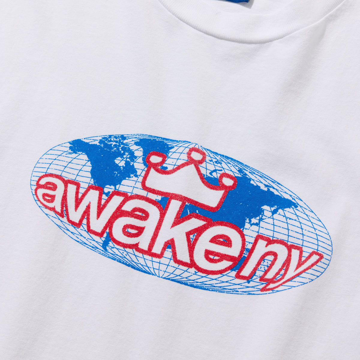 Detalle del estampado del globo terráqueo con awake ny y corona en rojo sobre la camiseta blanca
