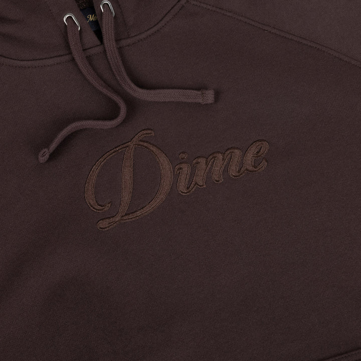 Detalle del logo Dime en cursiva bordado al tono sobre el parche de fieltro de la sudadera marrón