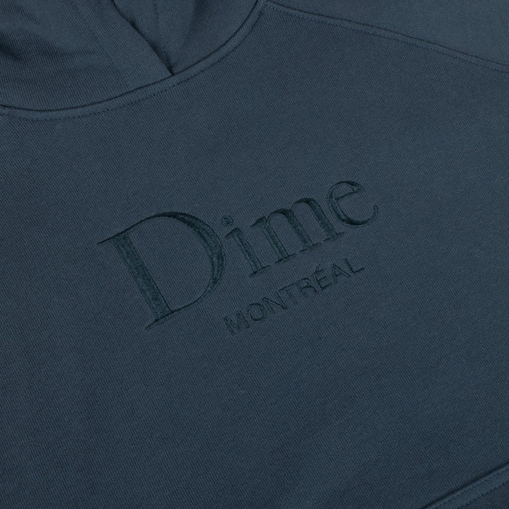 Detalle del logo Dime Montréal bordado al tono en el pecho de la sudadera azul marino