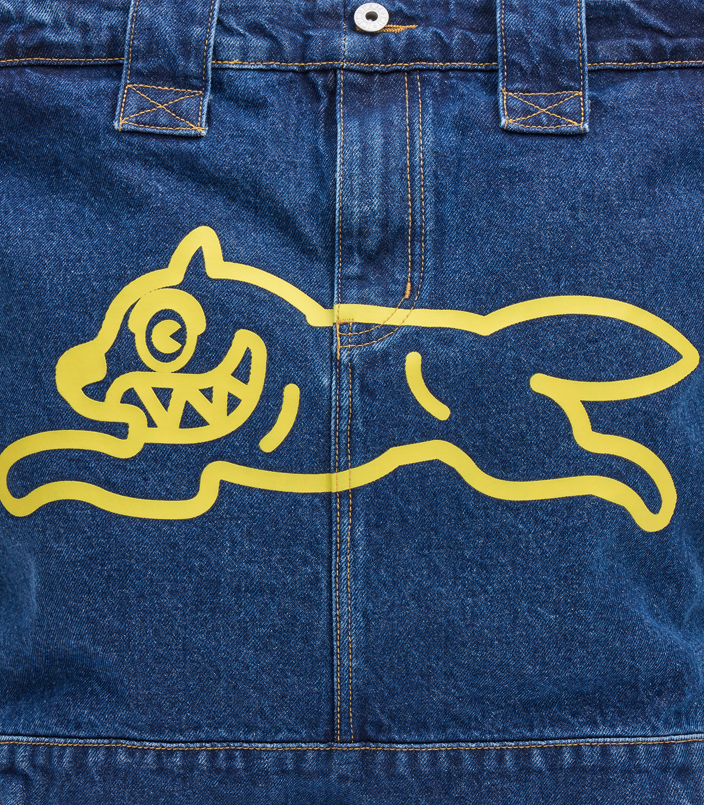 Detalle del logotipo Running Dog amarillo serigrafiado sobre el tejido de denim índigo