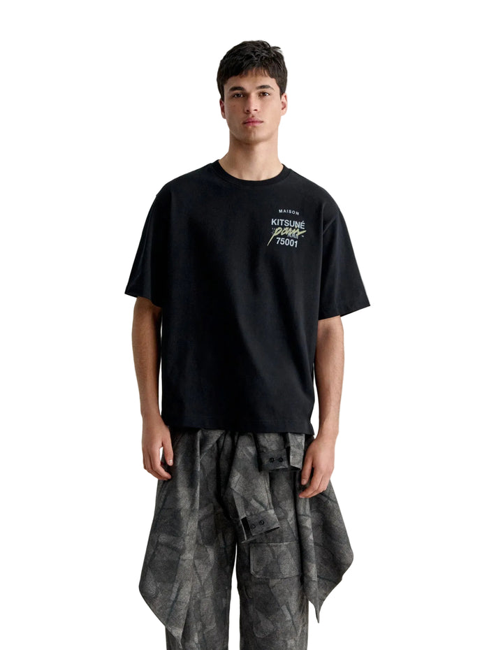 Hombre con la camiseta Maison Kitsuné MMII Profile Fox oversize negra y pantalón de camuflaje, look completo