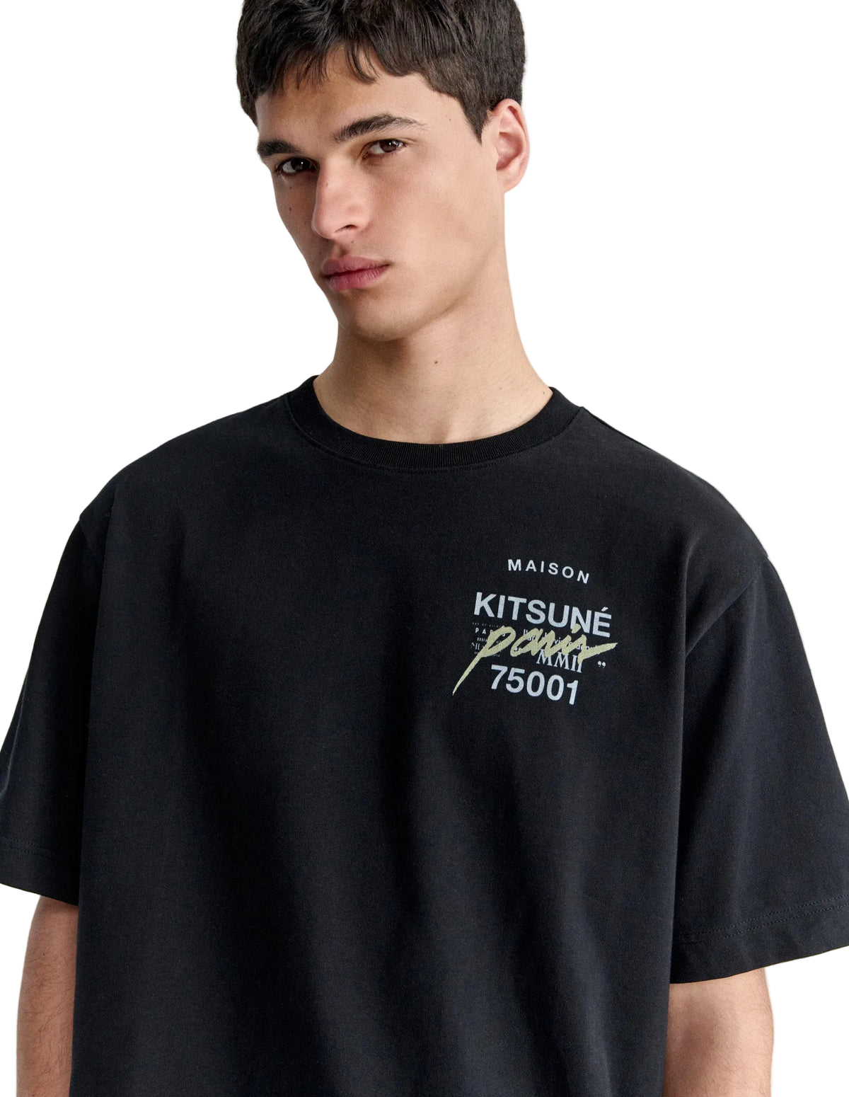 Hombre con la camiseta Maison Kitsuné MMII Profile Fox oversize negra, plano de medio cuerpo con el texto Kitsuné Paris 75001 en el pecho
