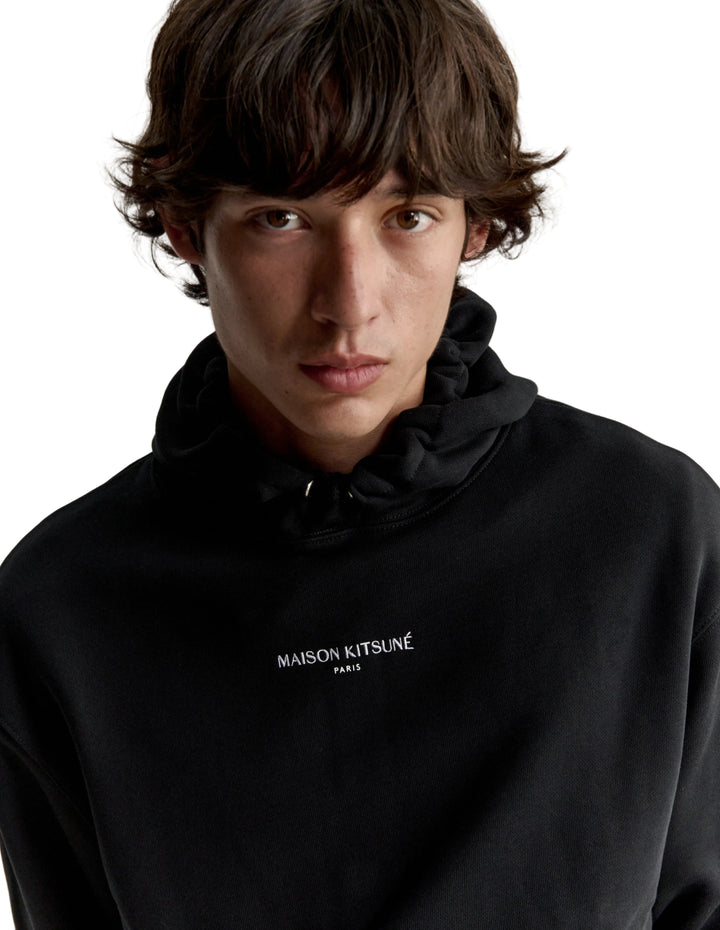 Hombre con la sudadera Maison Kitsuné Paris Comfort negra, plano de medio cuerpo con el logo en el pecho