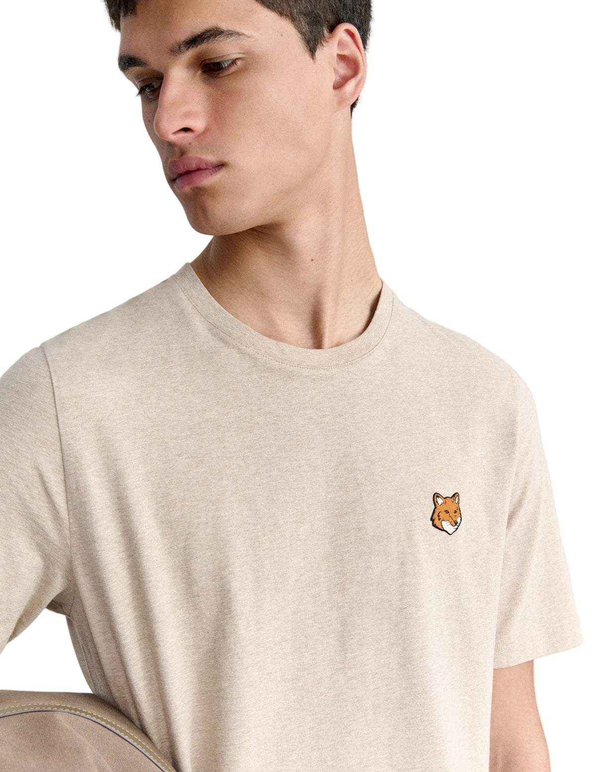 Hombre con la camiseta Maison Kitsuné Fox Head beige, plano de medio cuerpo con el parche del zorro en el pecho