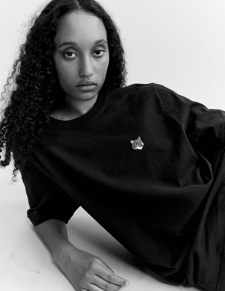 Persona tumbada con la camiseta Maison Kitsuné Fox Head, fotografía en blanco y negro