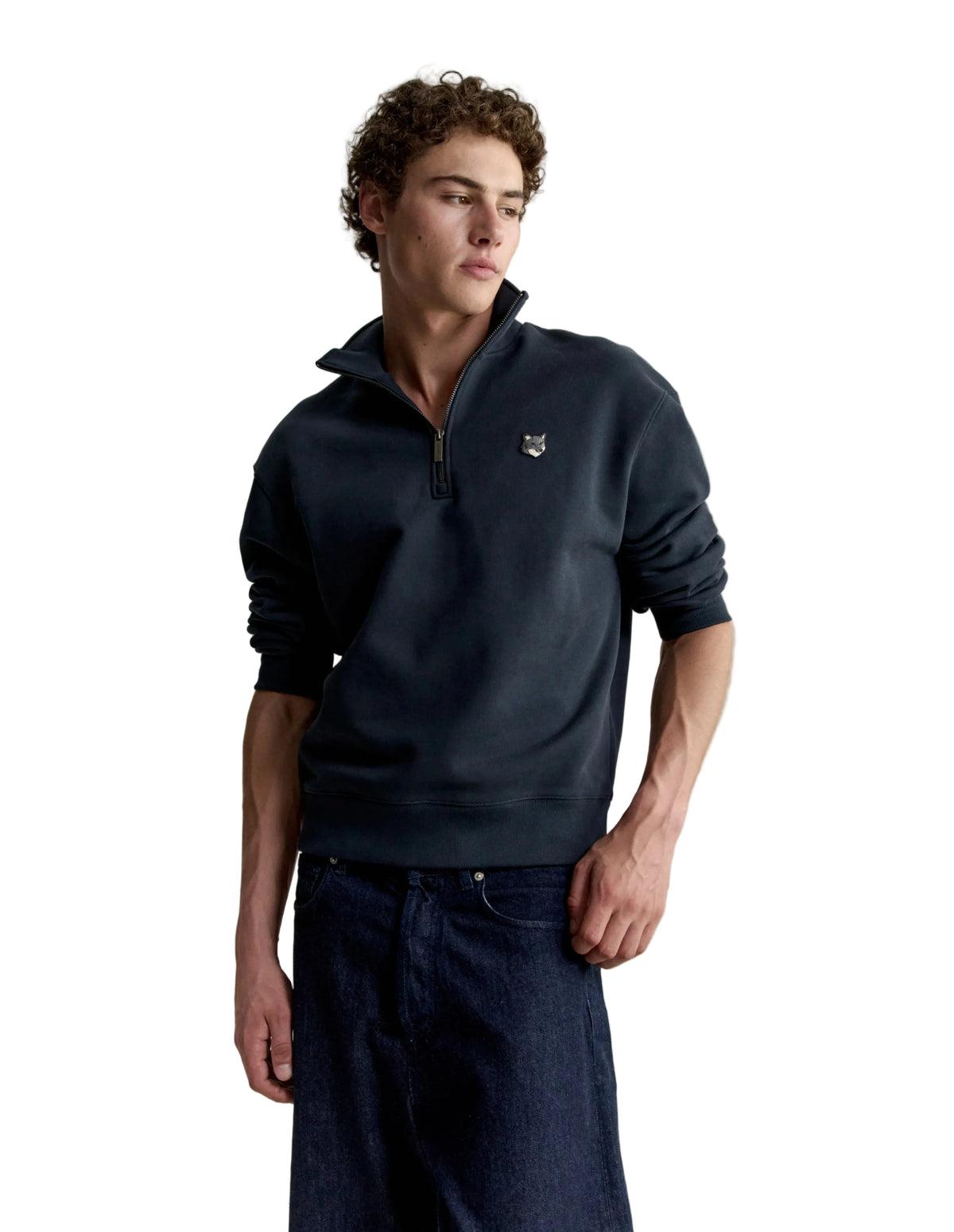 Hombre con la sudadera Maison Kitsuné Fox Head Half-Zip azul marino y pantalón oscuro, look completo