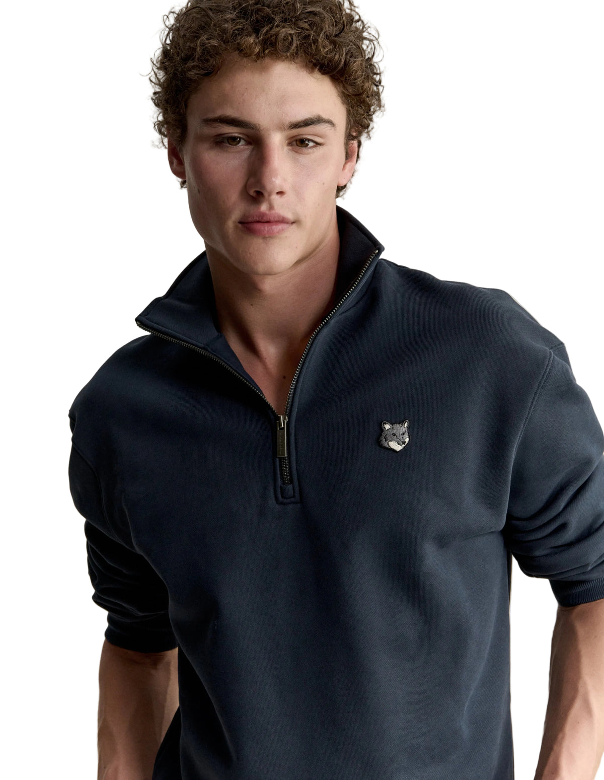 Hombre con la sudadera Maison Kitsuné Fox Head Half-Zip azul marino, plano de medio cuerpo con el parche del zorro en el pecho
