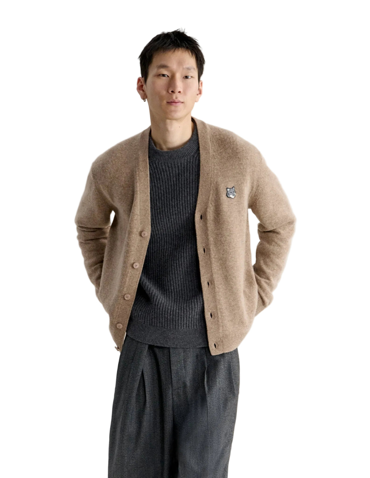 Hombre con el cárdigan Maison Kitsuné Fox Head Lambswool beige abierto sobre camiseta oscura y pantalón gris, look completo