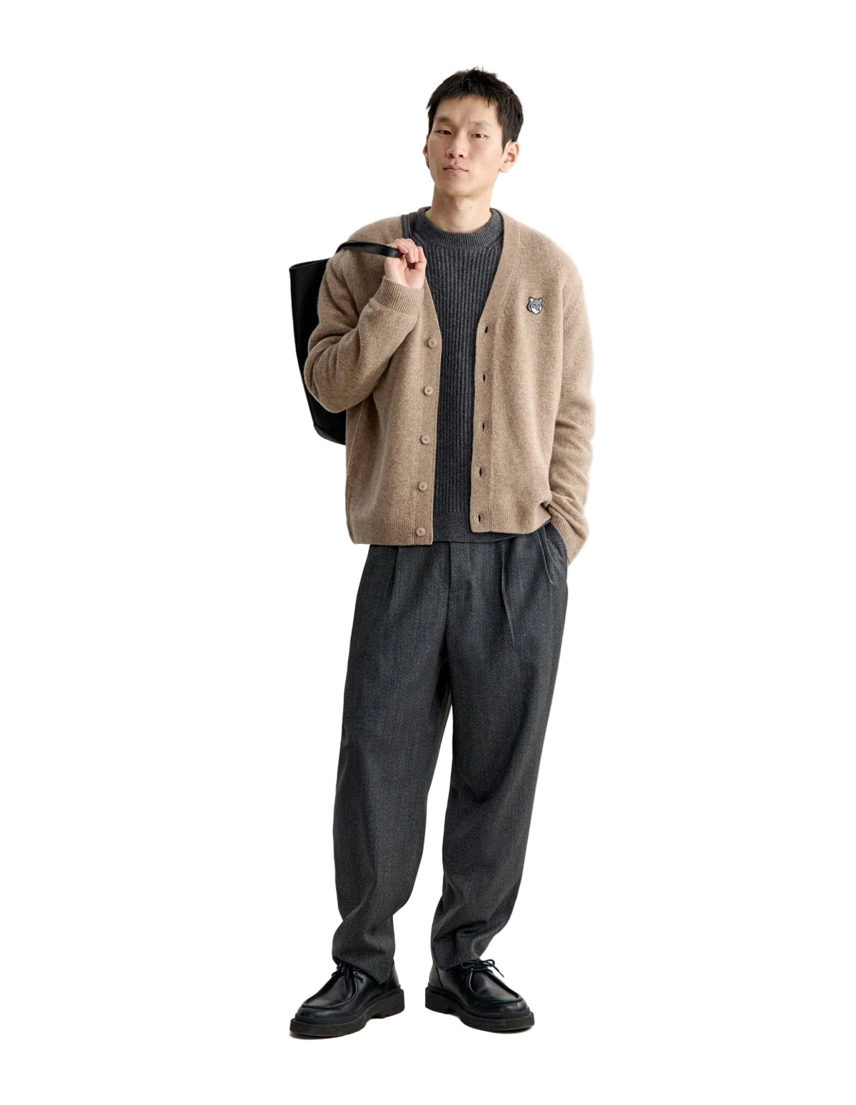 Hombre con el cárdigan Maison Kitsuné Fox Head Lambswool beige y pantalón gris, vista frontal de cuerpo entero