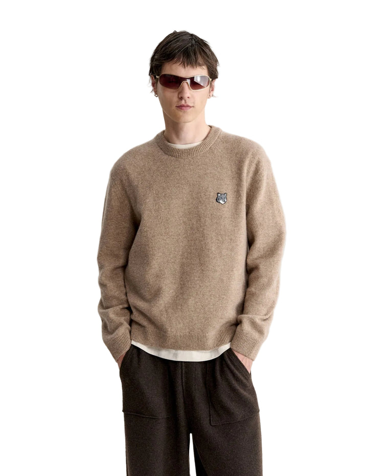 Hombre con el jersey Maison Kitsuné Fox Head Lambswool beige y pantalón oscuro, look completo de cuerpo entero
