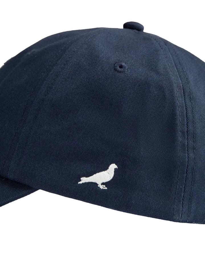 Detalle de la paloma Pigeon bordada en el lateral de la gorra Staple azul marino