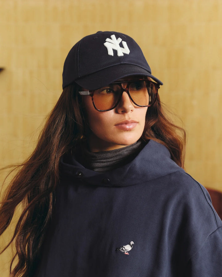 Persona con la gorra Staple NY Dad Cap azul marino y gafas de sol