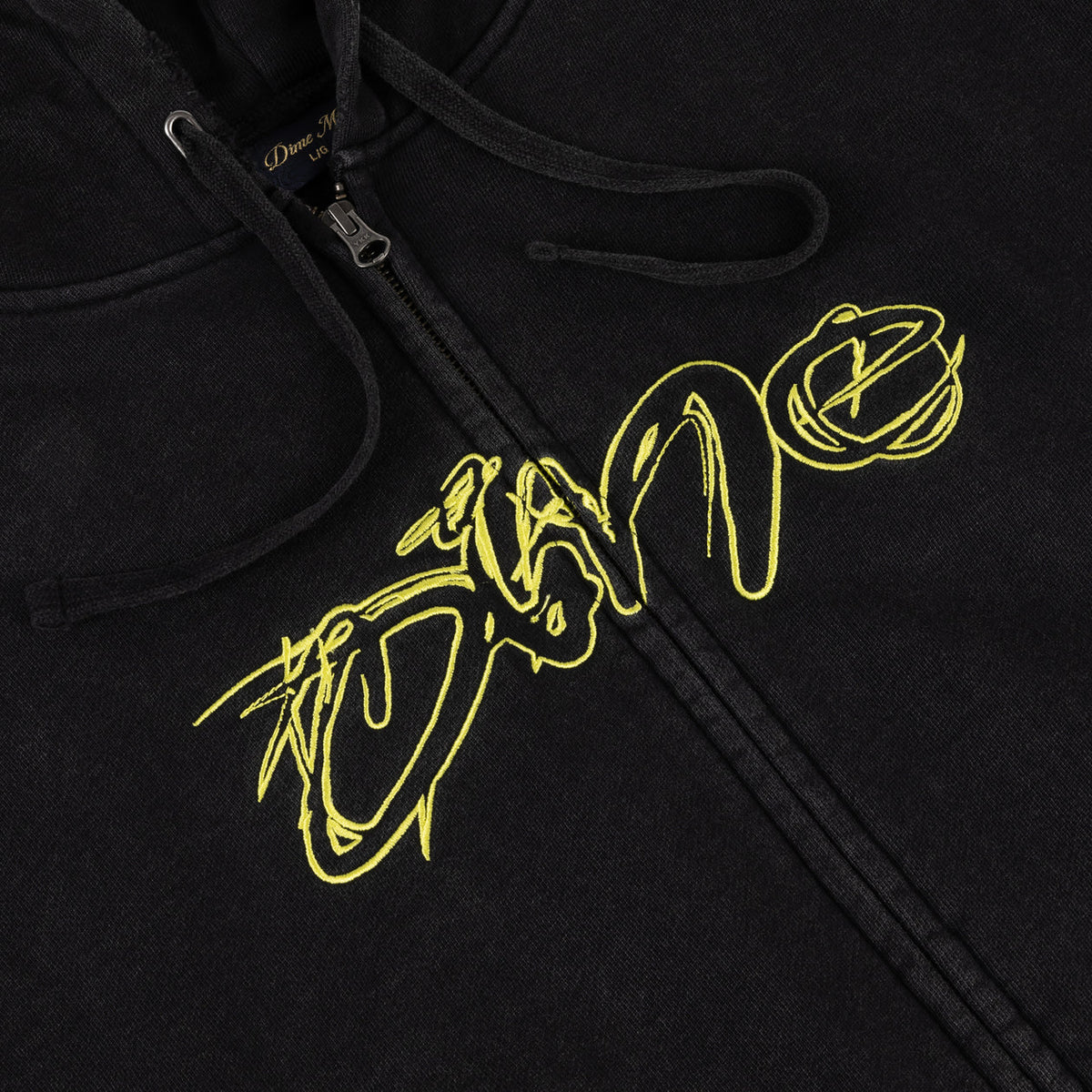 Detalle del logo Dime bordado en estilo grafiti lima sobre la sudadera negra lavada