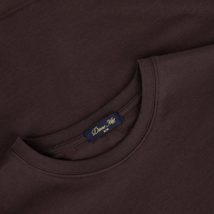 Detalle del cuello y la etiqueta Dime Ville de la camiseta marrón oscuro