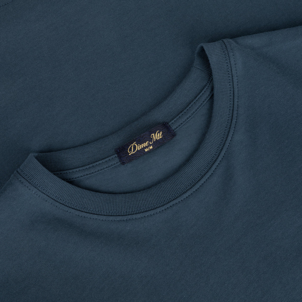 Detalle del cuello y la etiqueta Dime MTL de la camiseta Classic Plastic azul marino