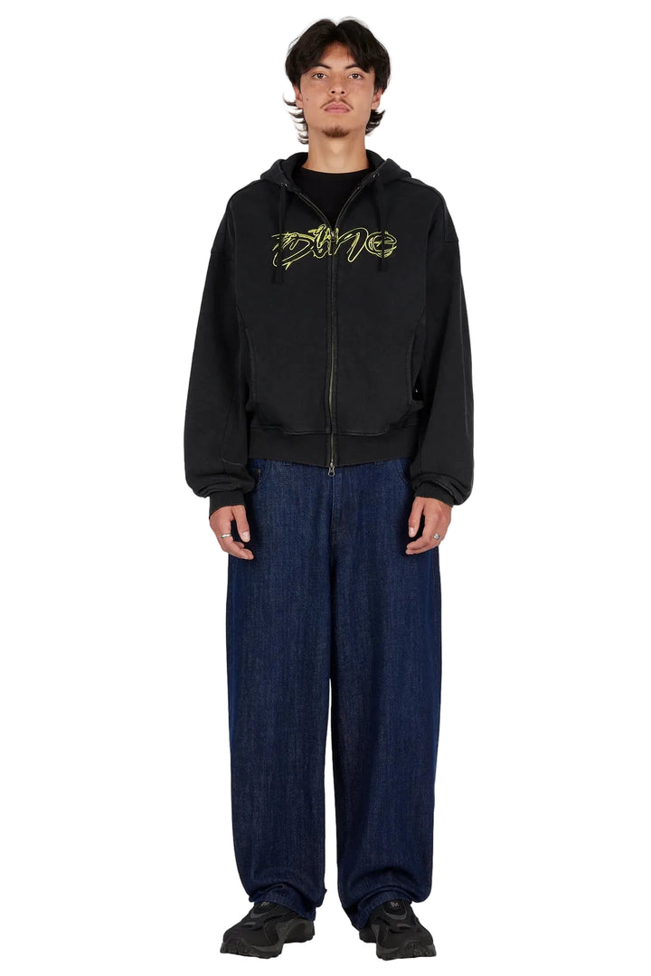 Modelo con sudadera Dime Distressed Terry Zip Hoodie negra y pantalón ancho azul, vista frontal