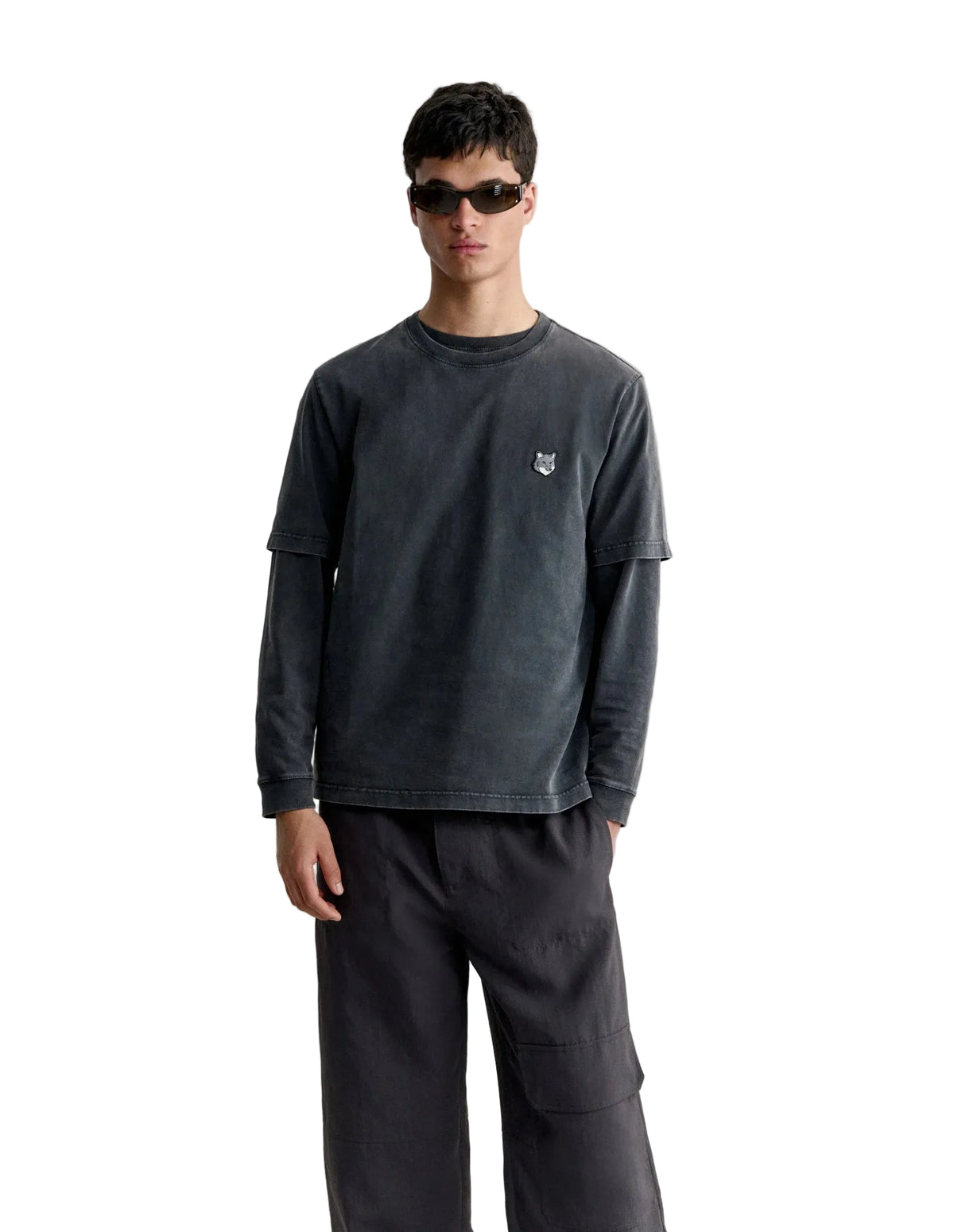 Hombre con la camiseta Maison Kitsuné Fox Head Faded en gris oscuro y pantalón gris, vista frontal de cuerpo entero