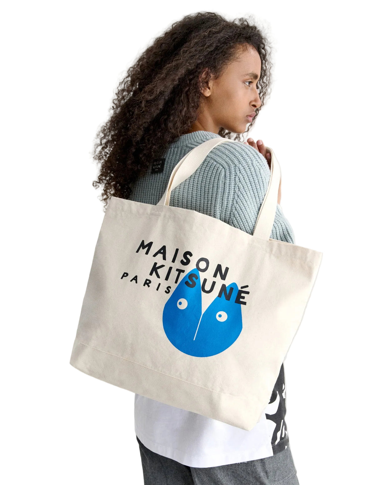 Modelo llevando al hombro el tote bag Maison Kitsuné ecru con estampado azul