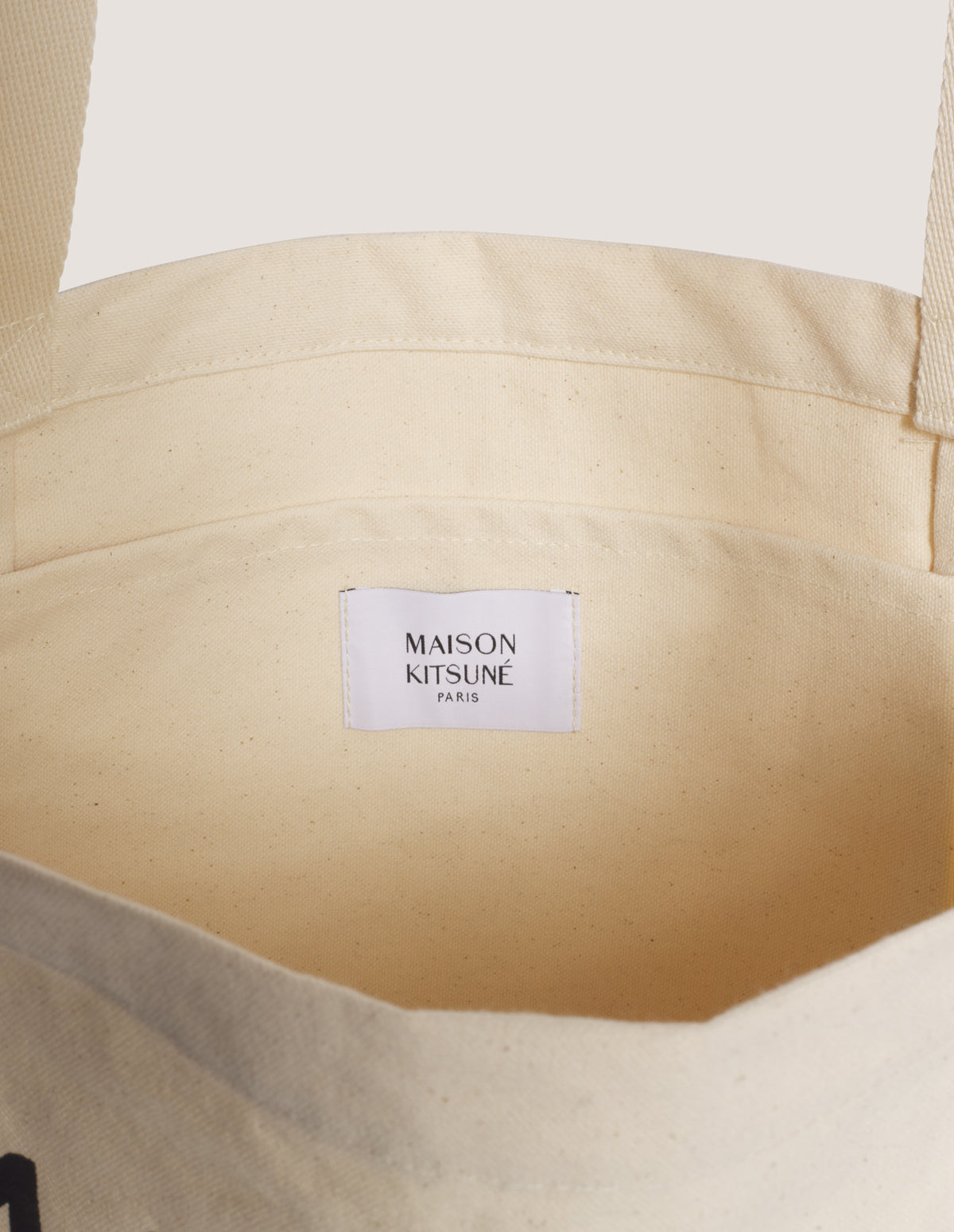 Interior del tote bag Maison Kitsuné con bolsillo plano y etiqueta de la marca